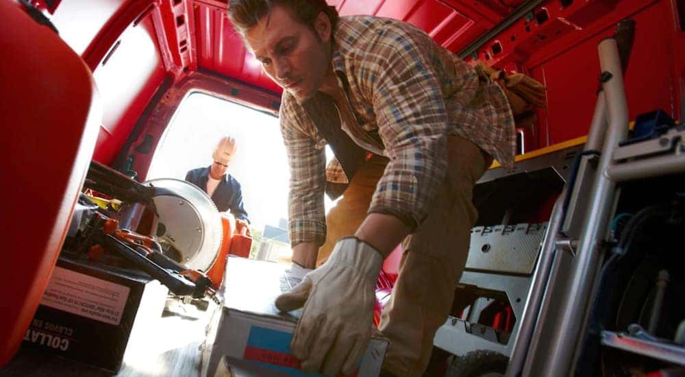 Men are shown loading building tools from the inside of a 2019 red Chevy Cargo Van.