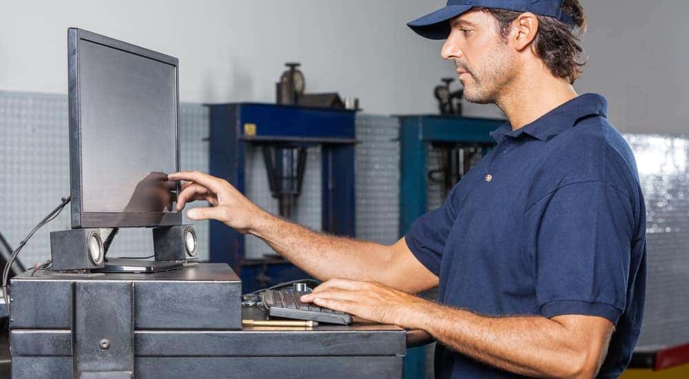 A mechanic is at a computer station setting up a maintenance schedule. 