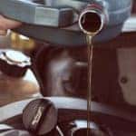 A mechanic is pouring oil into a vehicle for a quick lube.