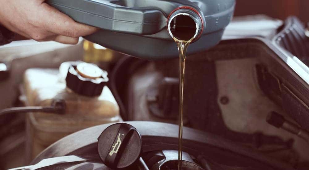 A mechanic is pouring oil into a vehicle for a quick lube.