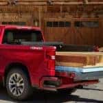 A couple is loading wood into the back of their red 2019 Chevy Silverado 1500.