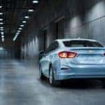 A silver 2017 Chevy Cruze is parked in a dimly lit parking garage. Used car values for the Cruze depend on many factors.