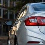 A silver 2017 Chevy Cruze is parked in front of an apartment building with the image zoomed on the driver side tail light.