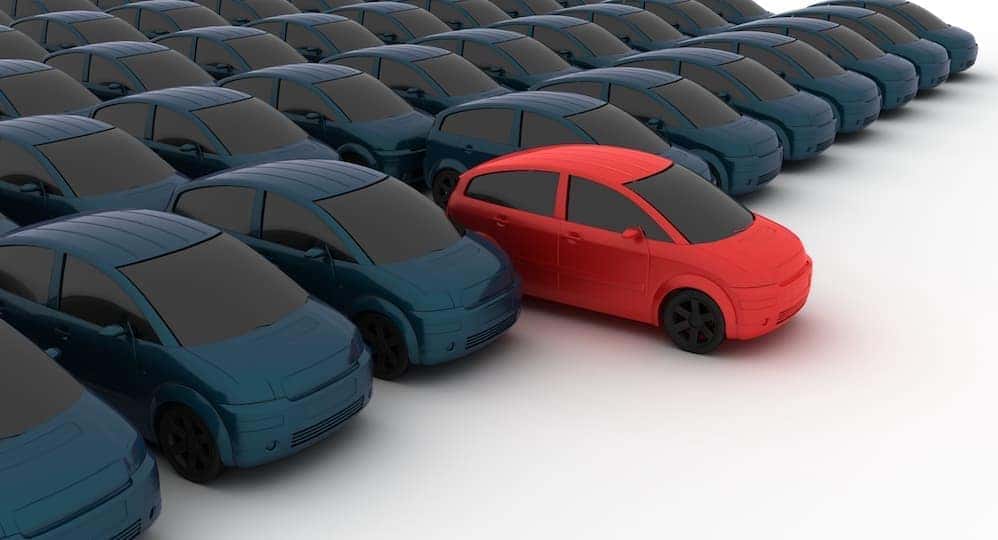 There is one red car in front of rows of black cars.