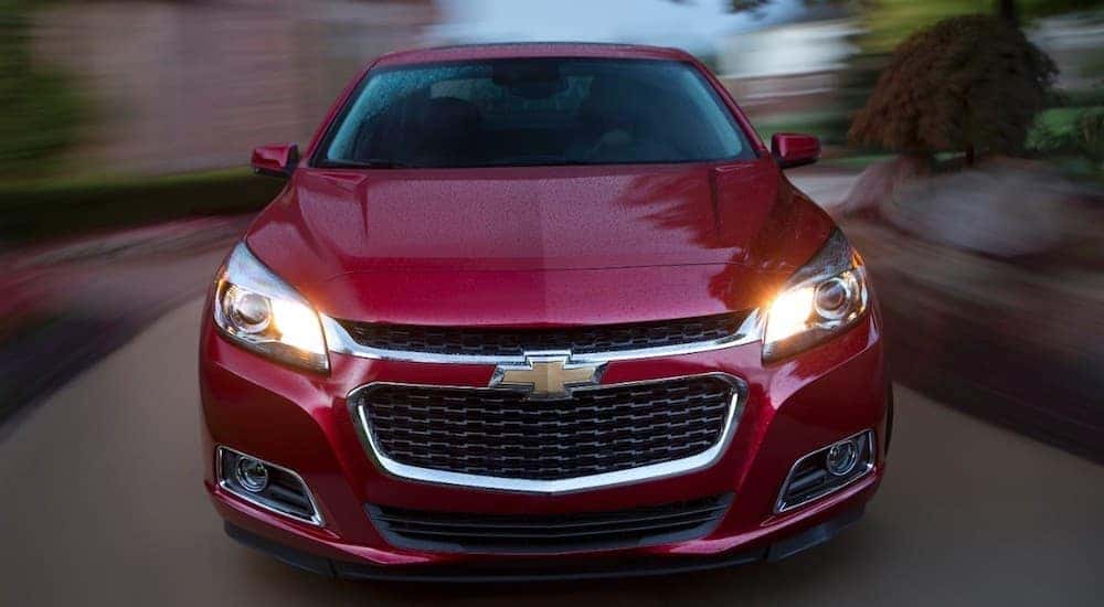 A red 2015 Chevrolet Malibu is driving fast down a road after leaving a buy here pay here Louisville dealership.