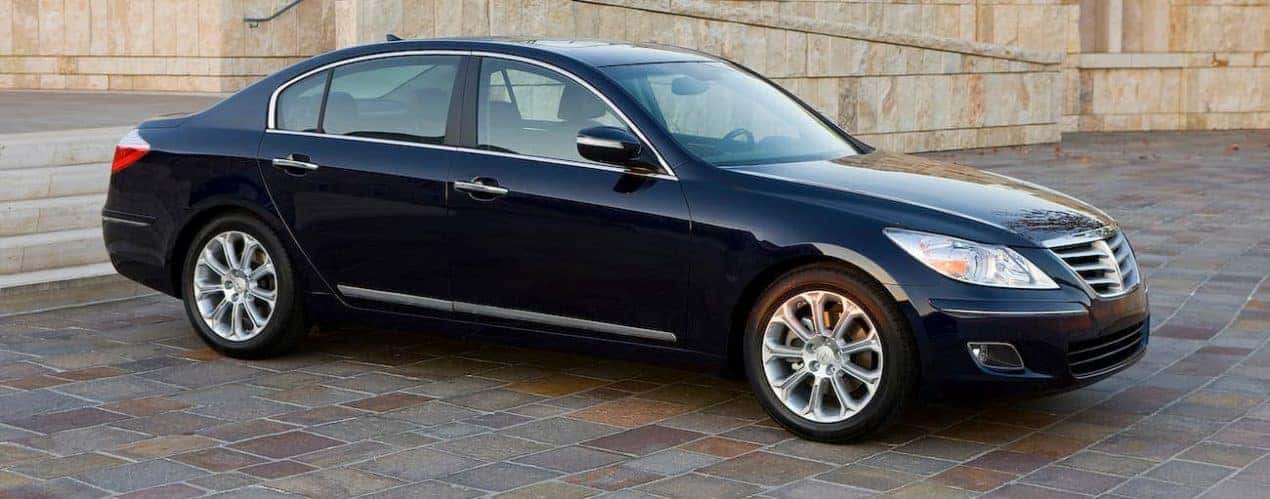 A black 2009 used Hyundai Genesis is parked on stone pavers.
