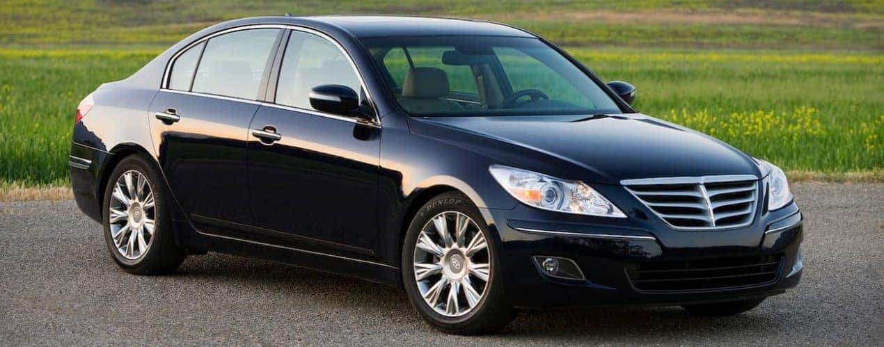 A black used 2011 Hyundai Genesis is parked in front of grass near Cincinnati, OH.