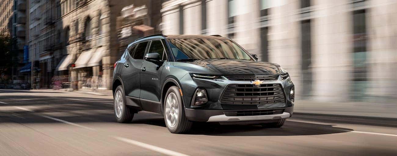 A green 2019 Chevy Blazer, which wins when comparing the 2019 Chevy Blazer vs 2019 Hyundai Santa Fe is driving down a street in Cincinnati, OH. 
