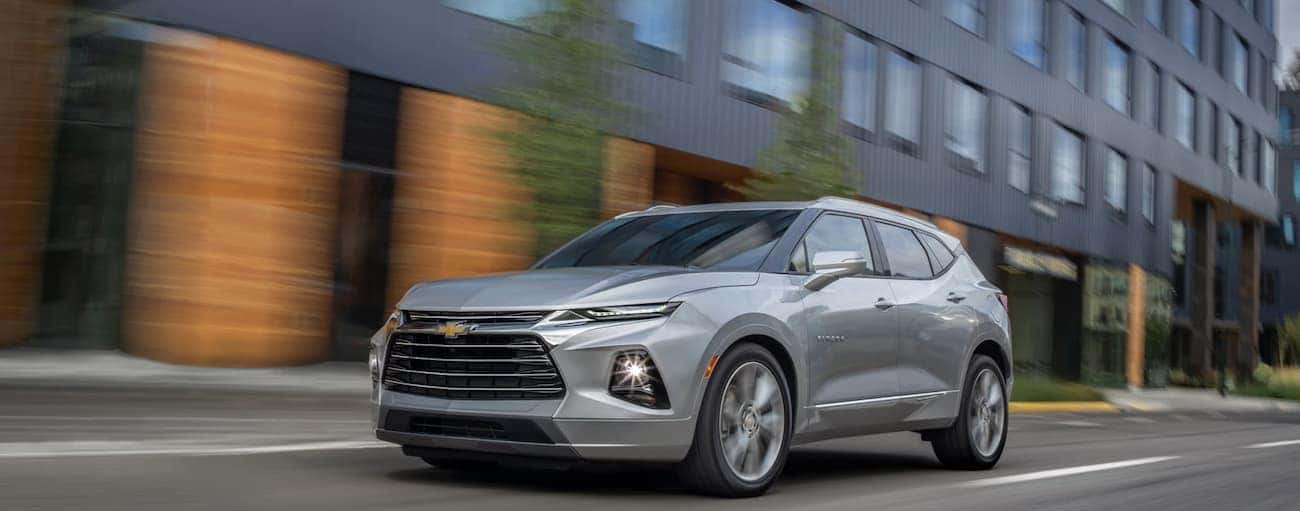 A grey 2019 Chevy Blazer, which wins when comparing the 2019 Chevy Blazer vs 2019 Jeep Cherokee, is driving past a black building near Cincinnati, OH.