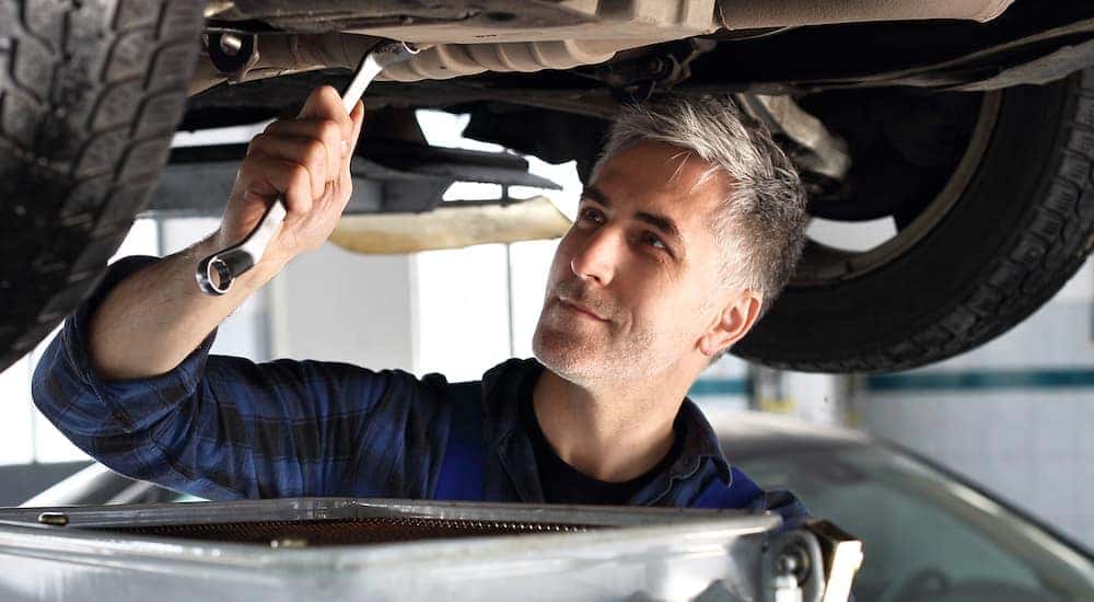 A mechanic is under a car performing a quick oil change near me in Cincinnati, OH.