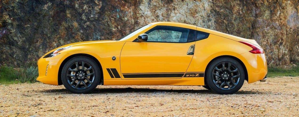 A yellow 2018 used Nissan 370Z is parked in front of a rock cliff.