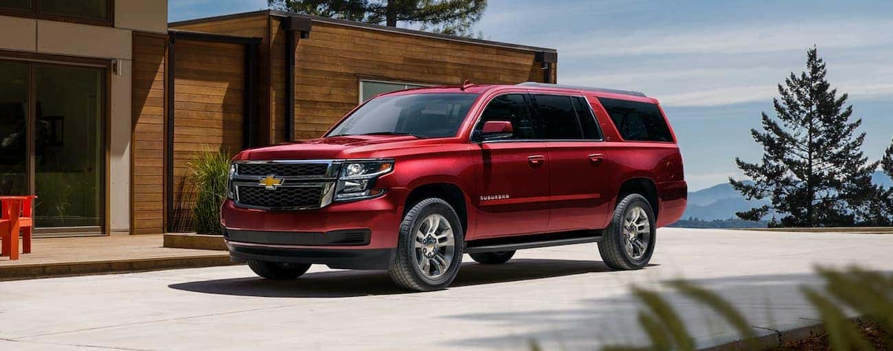 A red 2020 Chevy Suburban LT is parked in front of a modern home.