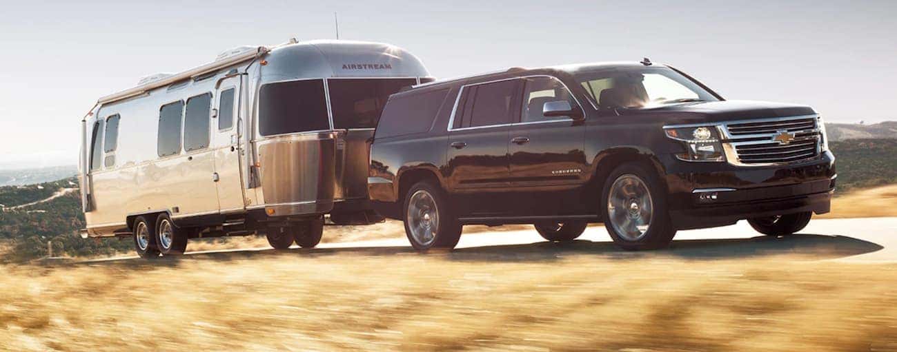 A black 2020 Chevy Suburban is towing an Airstream up a hill outside of Cincinnati, OH.