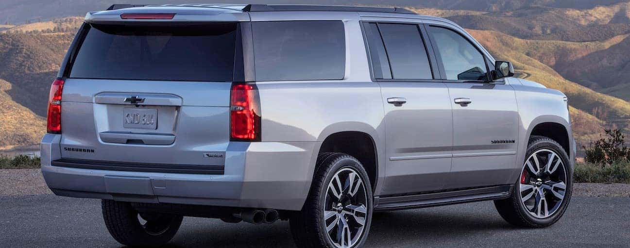 A silver 2020 Chevy Suburban is parked in front of mountains during sunset.