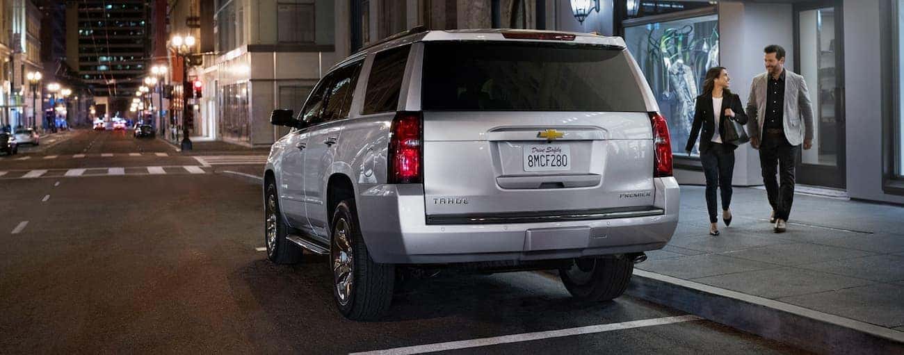 A silver 2020 Chevy Tahoe Premier is shown from the rear parked on a dark, city street.