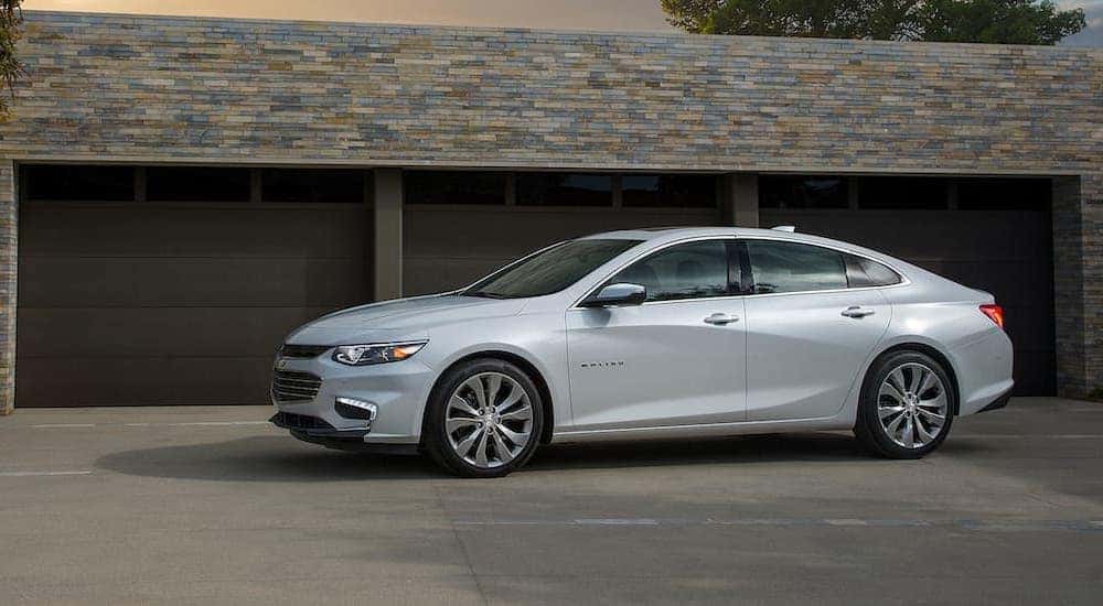 A white 2016 Chevy Malibu is parked outside of a garage at a home near Cincinnati, OH.