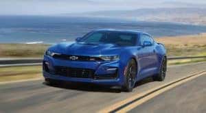 A blue 2020 Chevy Camaro SS is driving past the ocean.
