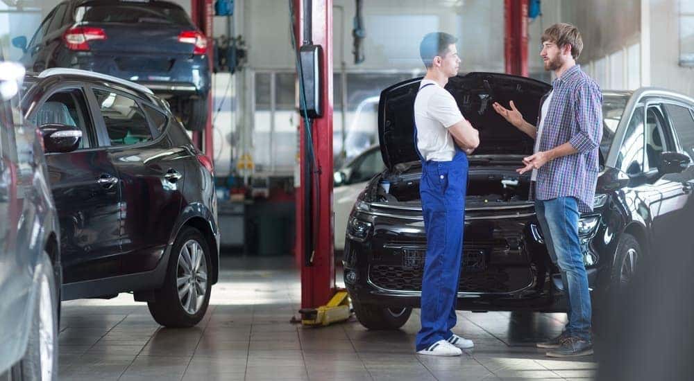 A customer is asking a mechanic, while on his search for the best local mechanic in Cincinnati, OH, questions about his work in a garage. 
