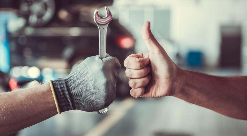 A mechanic's hand and a customer's hand are giving the thumbs up.