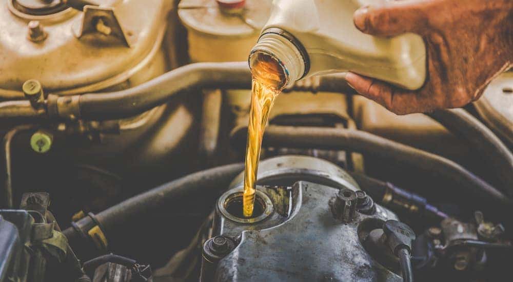 A local mechanic in Cincinnati, OH, is pouring oil into a car's engine.