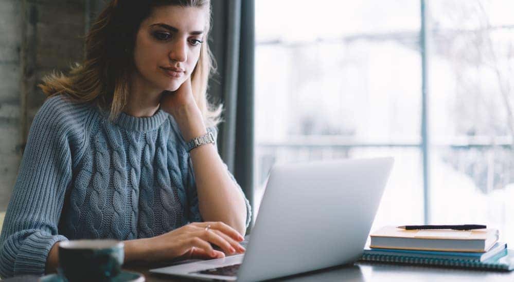 A woman is shown searching for the best oil change prices in Cincinnati, OH, on her laptop.