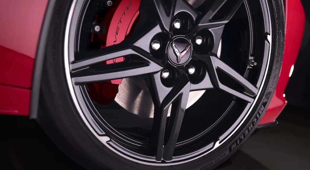 A close up view of a performance tire on a black wheel, which is a popular upgrade for 2020 Chevy Corvette accessories, found on a red 2020 Chevy Corvette.