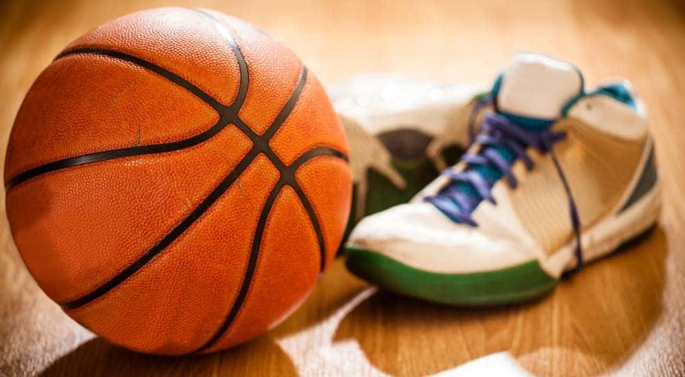 A basketball next to a pair of basketball shoes is shown.