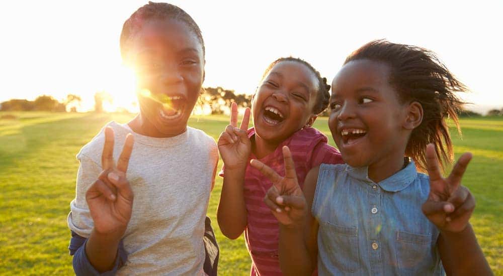 Three kids are giving the peace sign while visiting the Dayton, Ohio International Peace Museum.