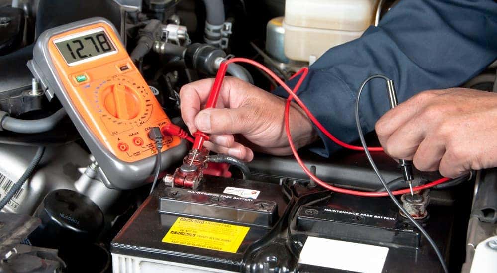 A mechanic is checking the battery voltage of a car battery. 