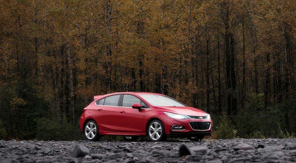A red 2018 Chevy Cruze, a popular pick among used cars near Dayton, Ohio, is parked in front of a wooded area.