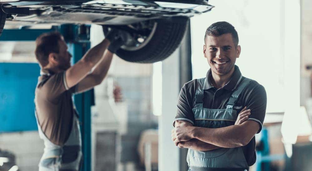 Smiling mechanics working on used cars in Columbus, Ohio on lifts