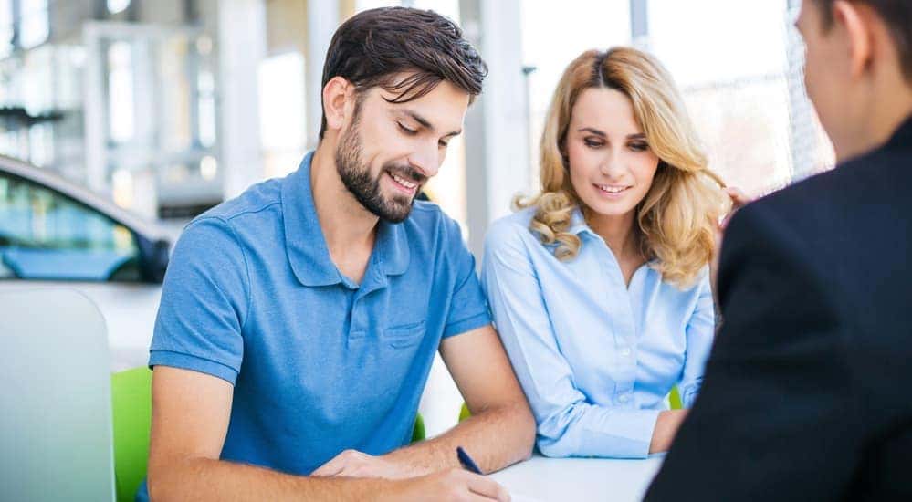 A couple is signing paperwork for a car that they're buying in Cincinnati, OH, with bad credit.