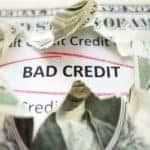 A dollar is ripped open with bad credit showing through the hole.