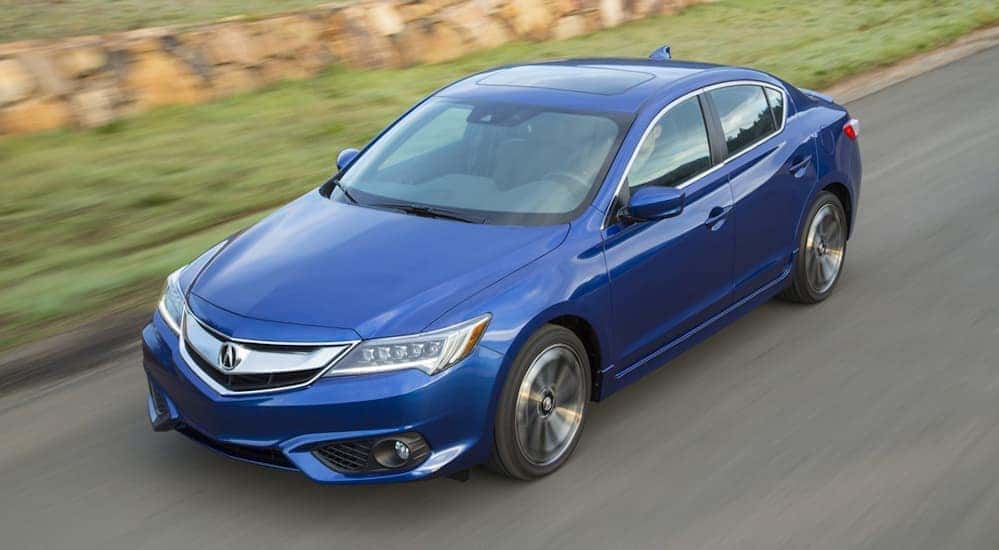 A birds eye view of a blue 2016 Acura ILX is shown driving on a grass lined road.