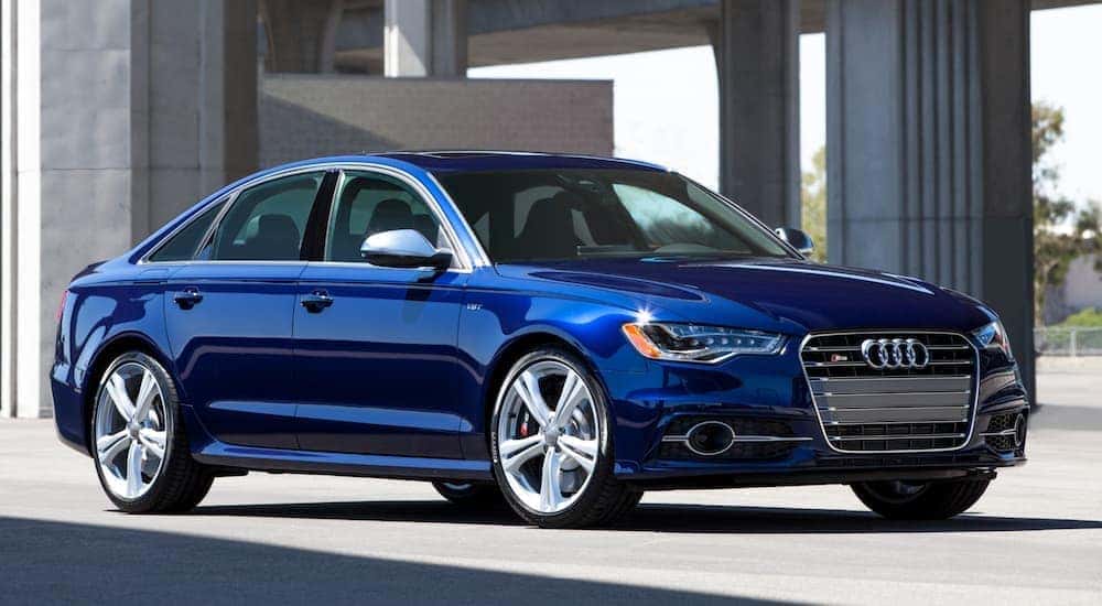 A blue 2017 Audi A6 is parked under a bridge.