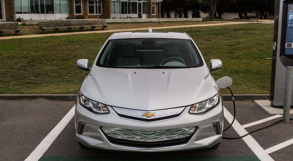 A silver 2017 Chevy Volt, which is a popular option among used cars, is parked in front of a school near Cincinnati, OH.