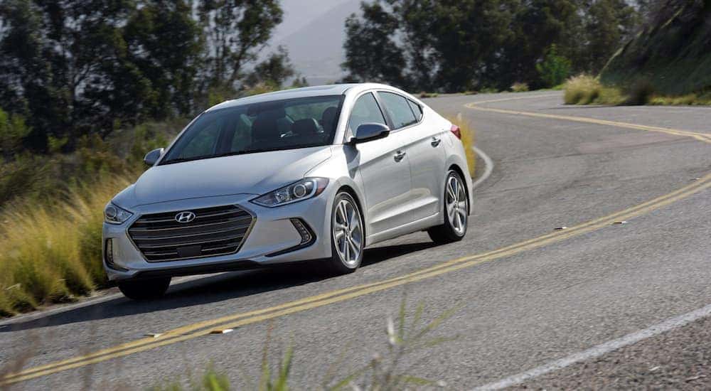 A silver 2018 Hyundai Elantra GT is driving on a tree lined road near Cincinnati, OH.