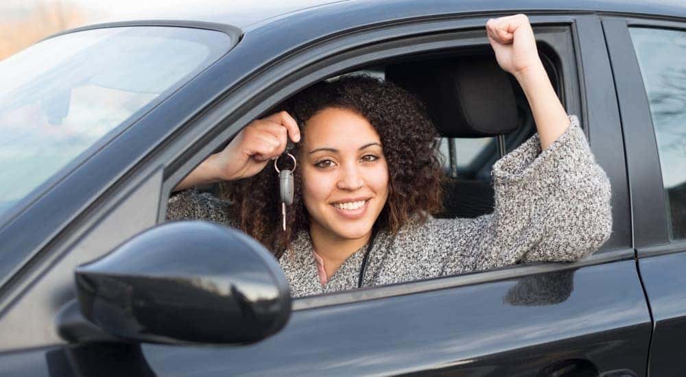 A woman is smiling as she holds up the keys to her new used car in Cincinnati, OH.