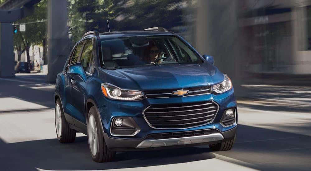 A blue 2020 Chevy Trax, which is a great Chevy SUV to buy in 2020, is driving next to a bridge near Cincinnati, OH.