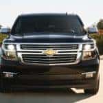 A black 2020 Chevy Suburban is facing forward while driving on a tree lined highway near Cincinnati, OH.