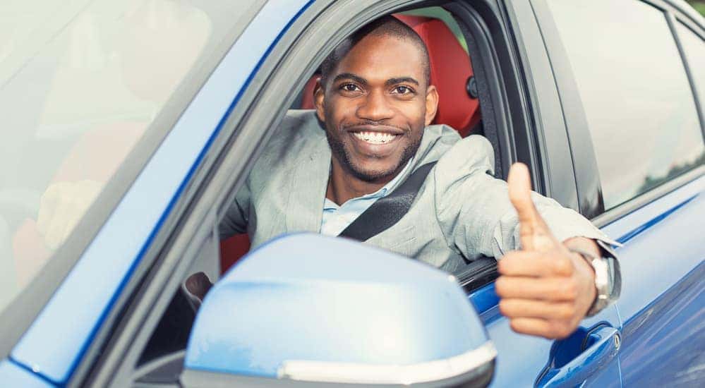 A man is smiling and giving the thumbs up after buying a used car at McCluskey Chevy.