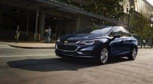 A blue 2018 Chevy Cruze, popular among used cars for sale in Ohio, is driving along a Cincinnati Street.