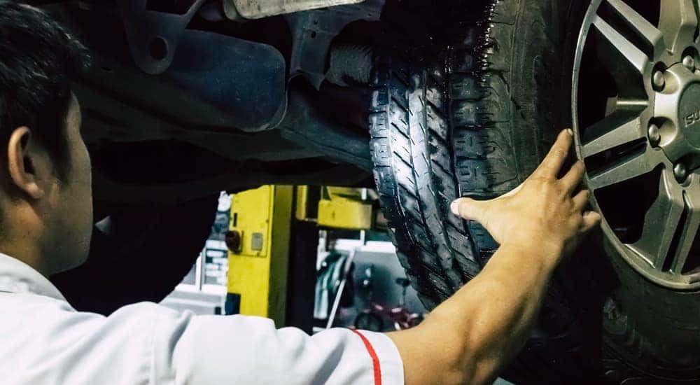 A mechanic is looking over a tire's tread. 