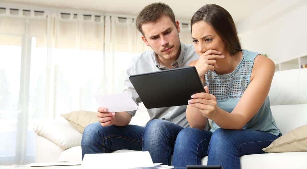 A stressed couple is looking at their bad credit score while trying to find used cars for sale in Ohio. 