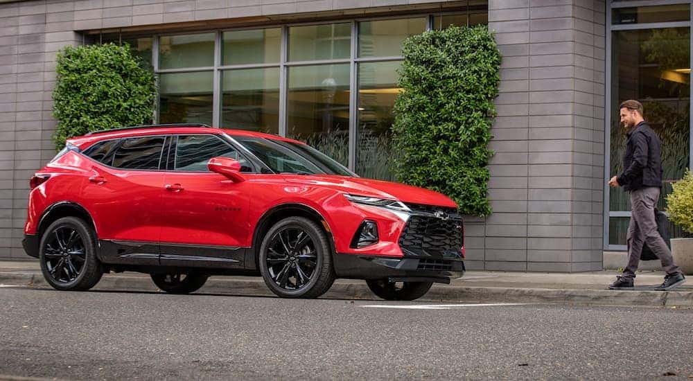 A red 2020 Chevy Blazer RS is parked in front of a city building in Cincinnati, OH, with a man walking toward it.