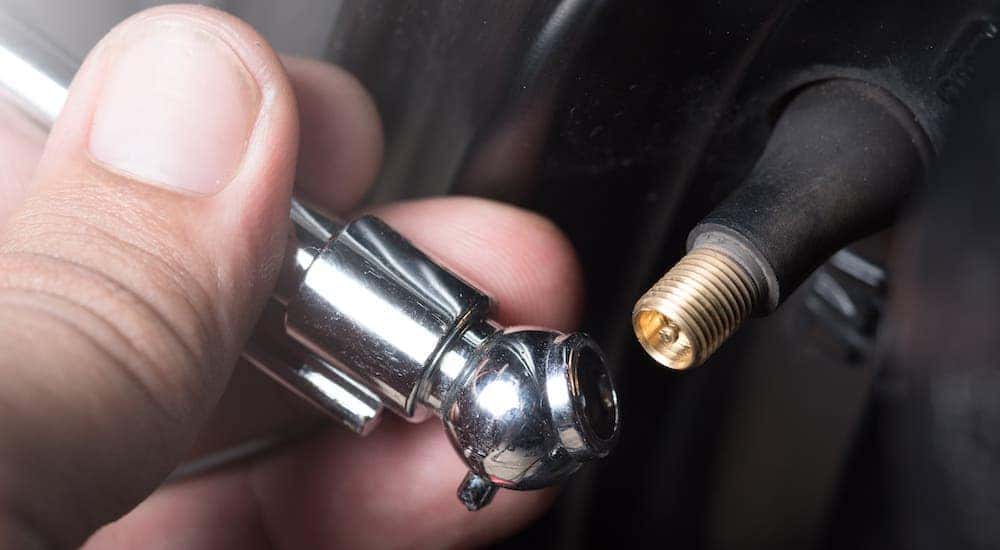 A closeup is shown of a hand checking the pressure of their tires in Cincinnati.