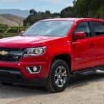 A red 2018 Chevy Colorado is parked in front of a farm.