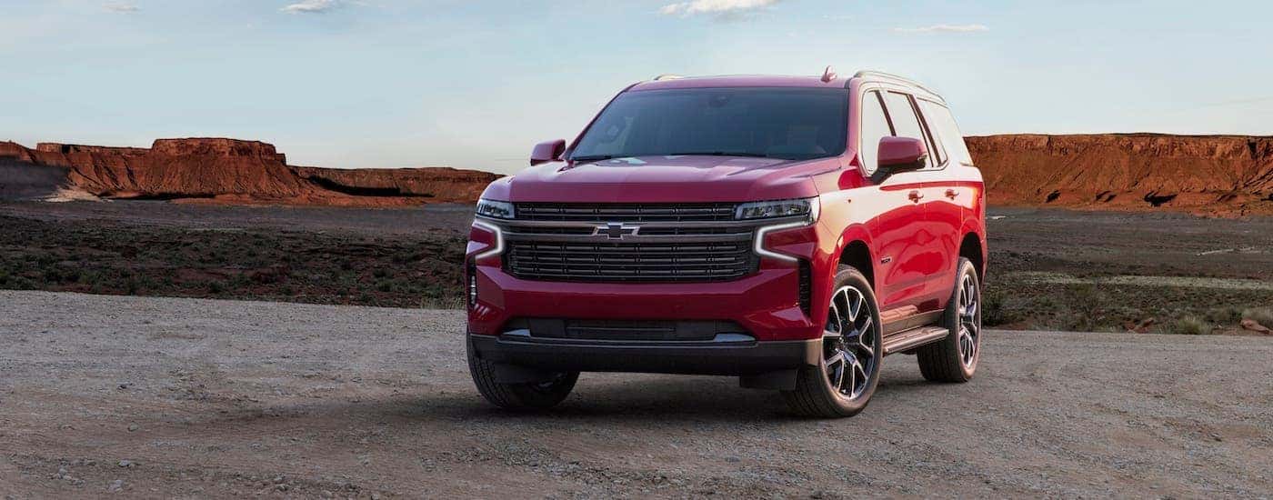 A red 2021 Chevy Tahoe RST is parked in a desert with mountains in the distance.