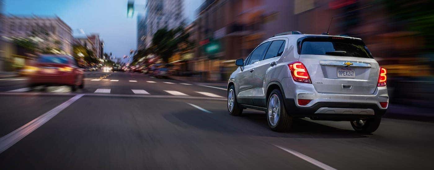A white 2020 Chevy Trax is driving on a city street after winning the 2020 Chevy Trax vs 2020 Honda HR-V comparison.