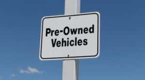 A white sign says 'Pre-owned Vehicles.'